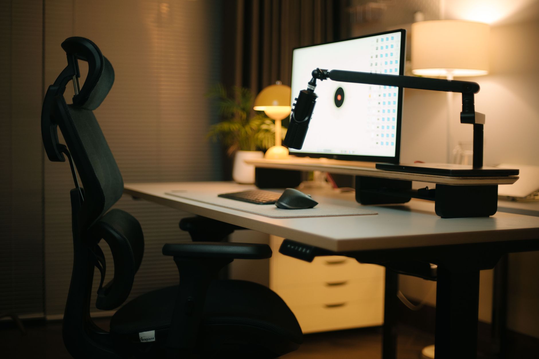 a home office with a standing desk, ergonomic chair, and lumbar support visible