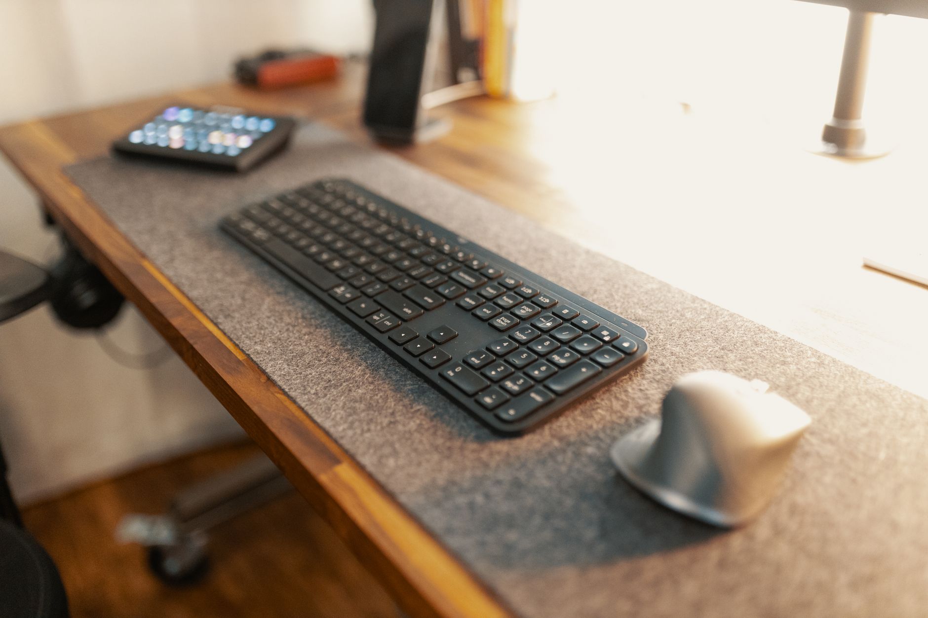 Gray cloth desk mat under a white keyboard and black mouse on wooden desk