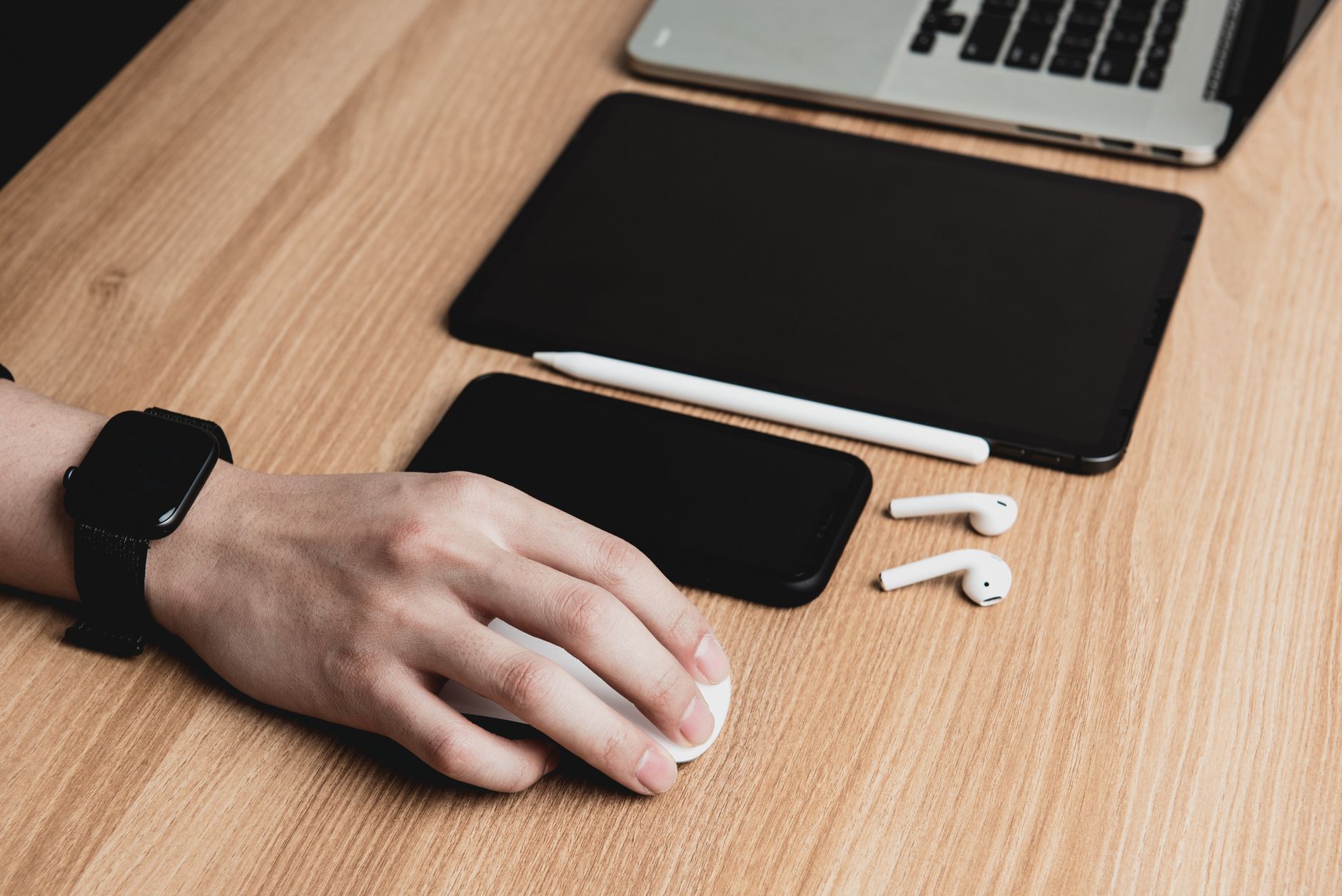 A person's hand resting on a gray trackball ergonomic mouse at a workstation.