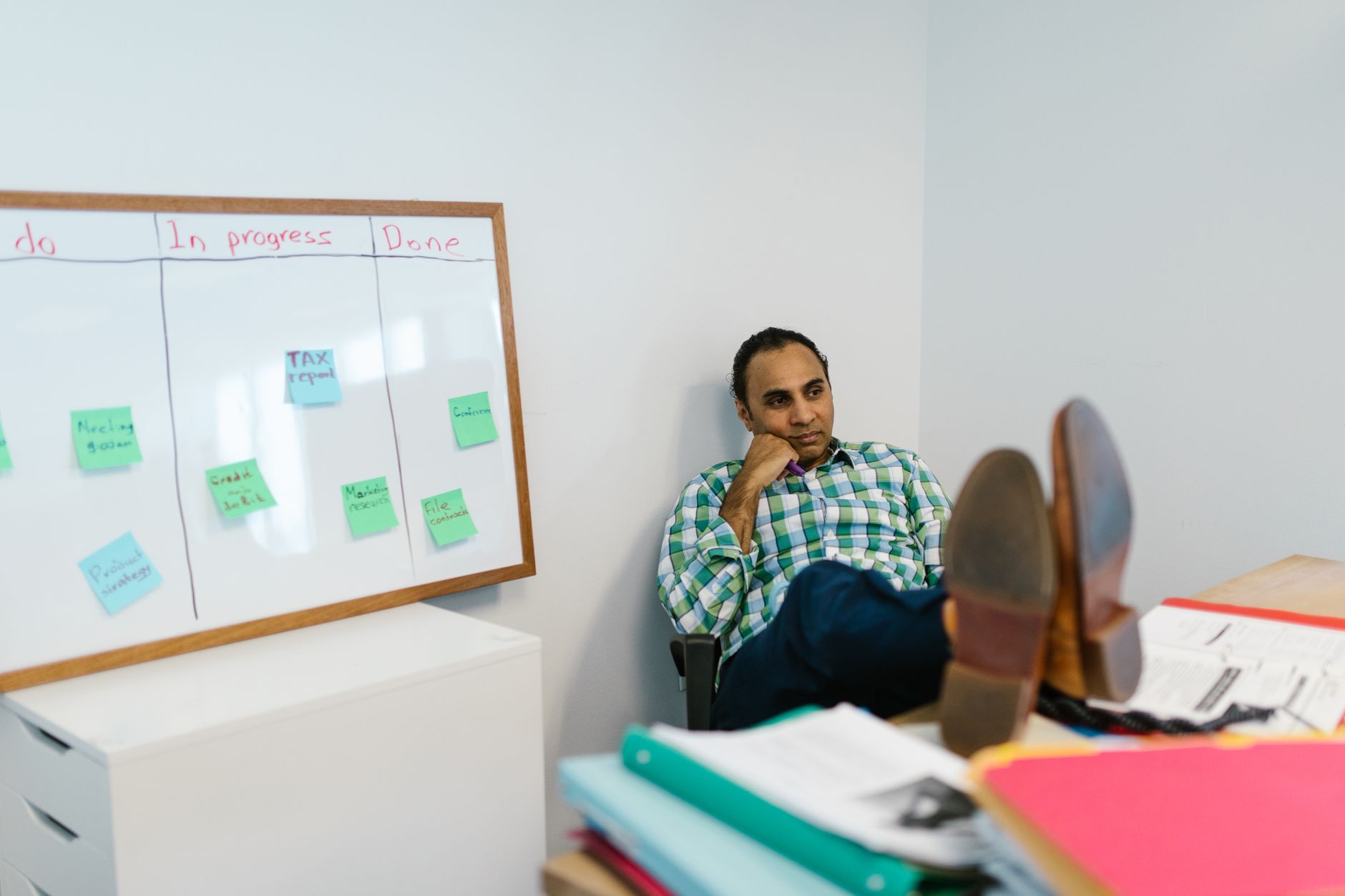 A person seated at an office desk with feet resting on a foam footrest under the desk