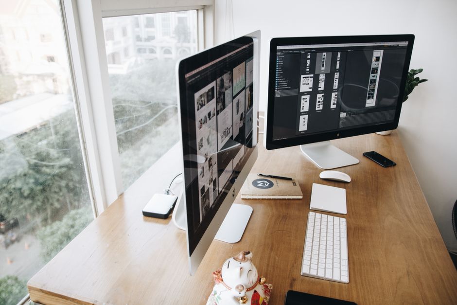 A well-organized modern office desk with dual computer screens and various devices.