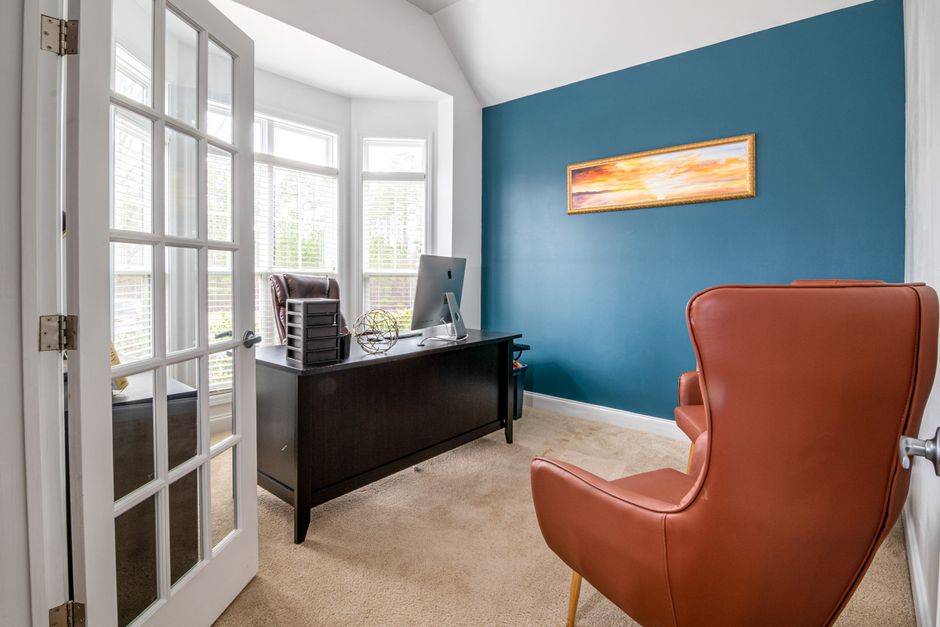 Bright office room with blue accent wall, featuring leather chair and desk in natural light.