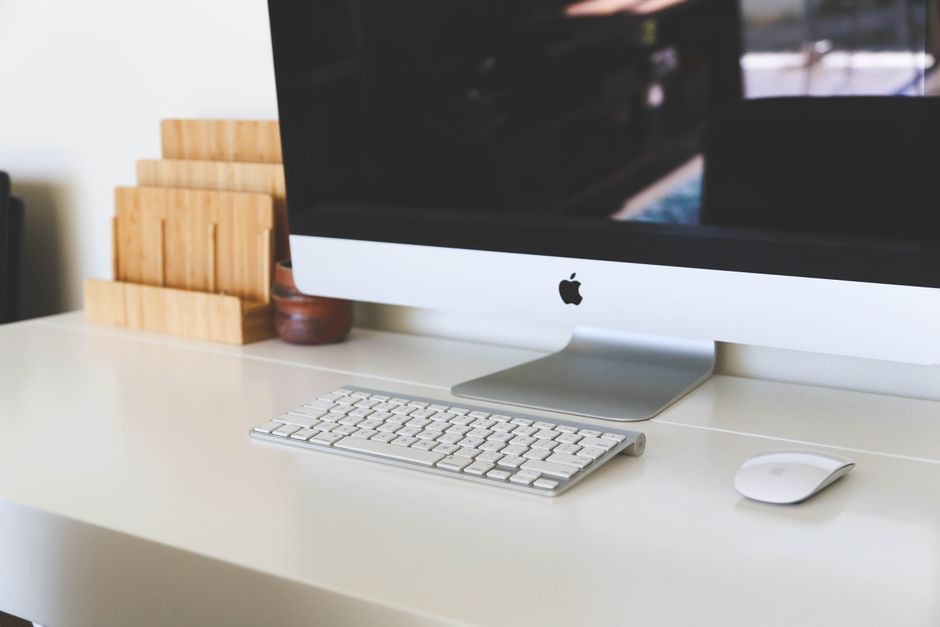 A clean and modern home office workspace featuring an iMac, keyboard, and magic mouse on a minimalist desk.