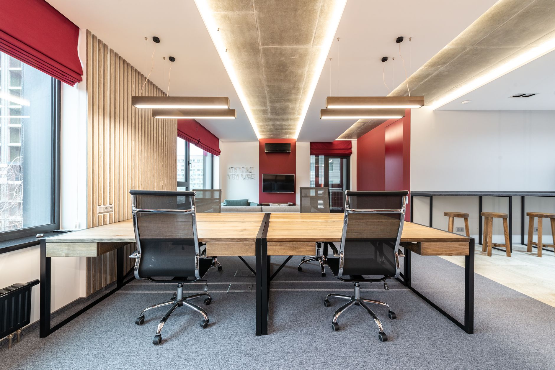 Black mesh ergonomic drafting stool standing next to a tall wooden work table