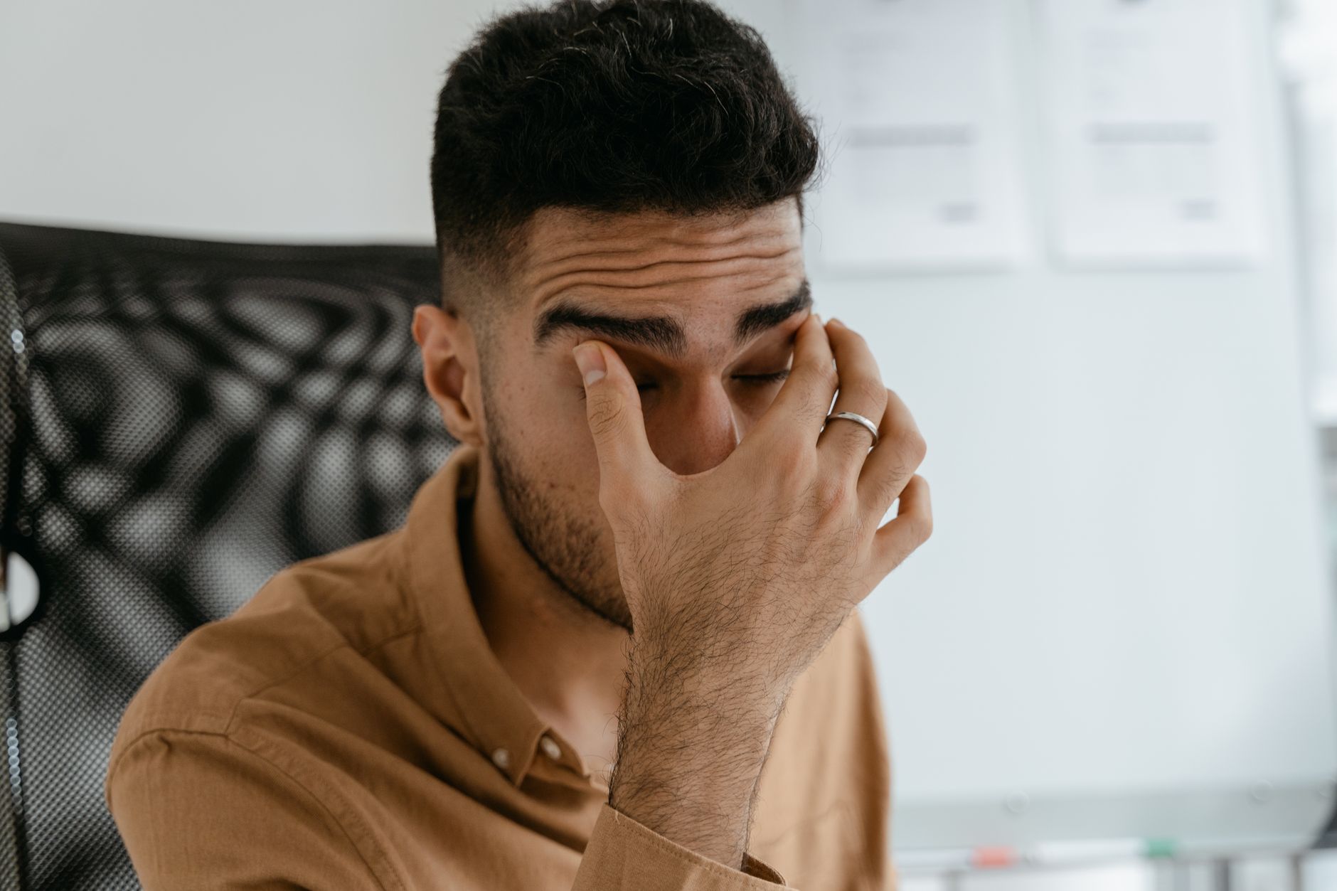 Office worker rubbing tired eyes while sitting in front of a computer monitor