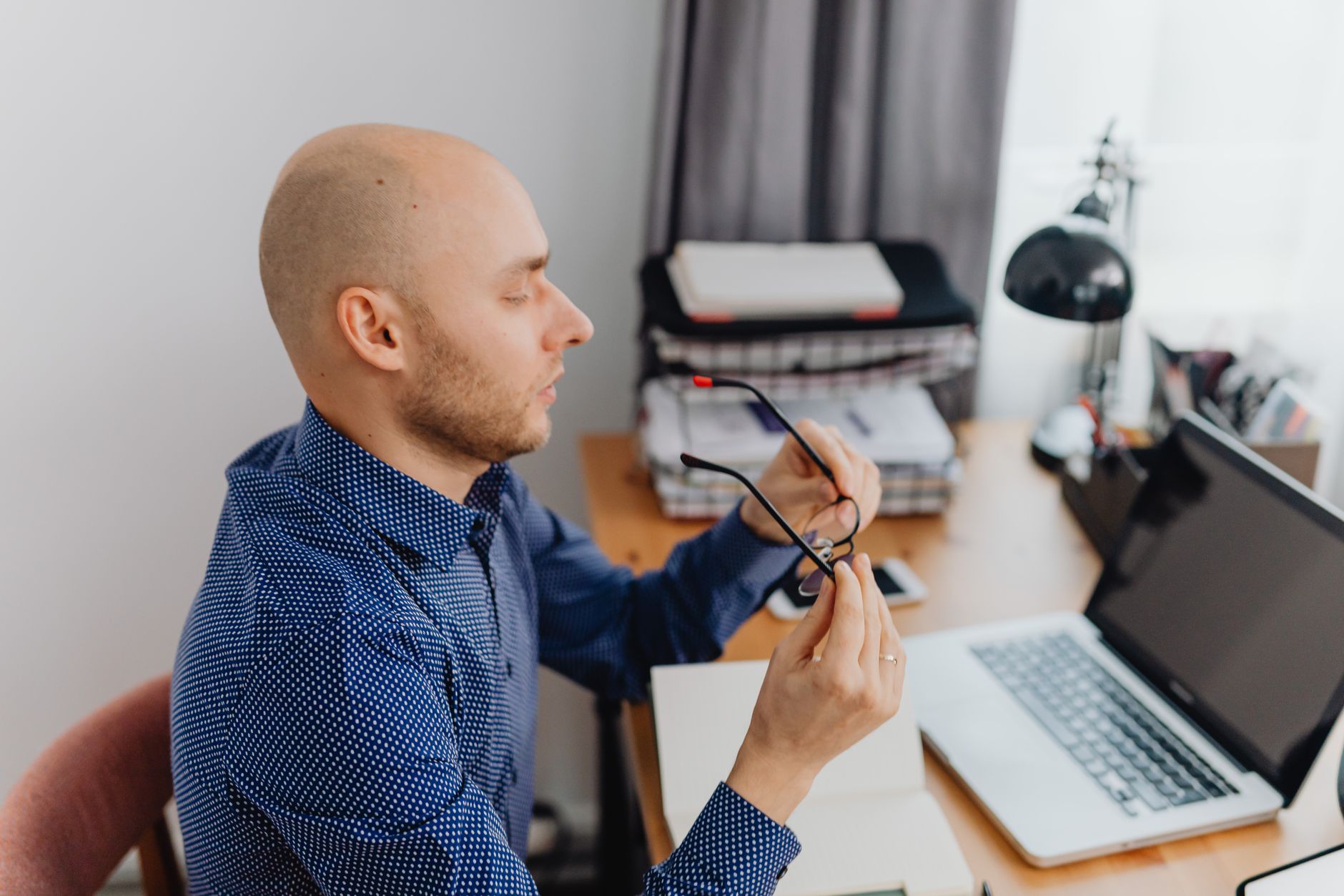 a person adjusting a desk lamp while working on a computer in a home office