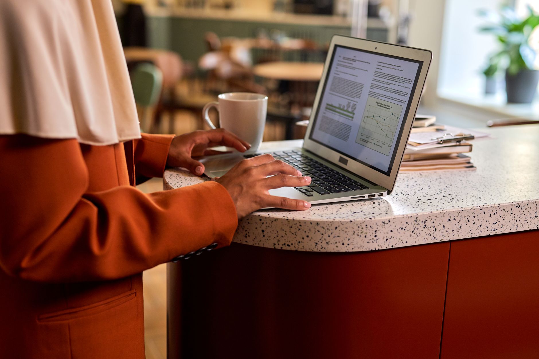 Woman standing at a raised platform on a desk while typing on a laptop